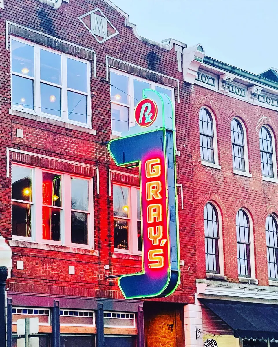 The Gray's neon sign and brick storefront at sunset.