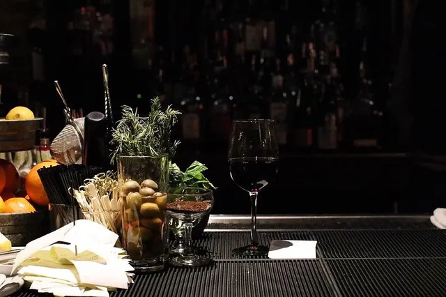 Bar service area with rosemary garnish, olives, and a glass of red wine.
