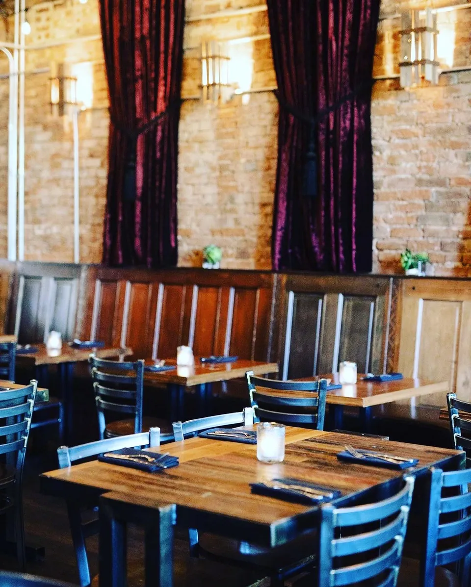The formal dining hall with tall burgundy curtains, exposed brick walls, and table seating.